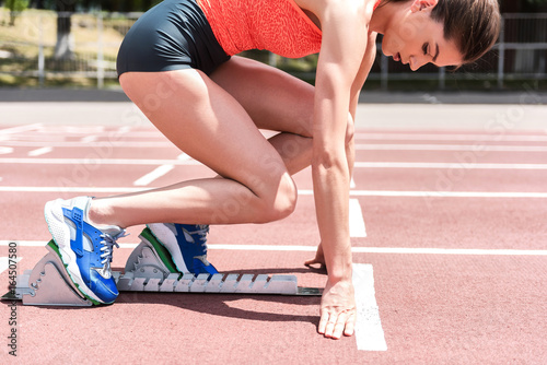 Confident female sprinter standing at starting position