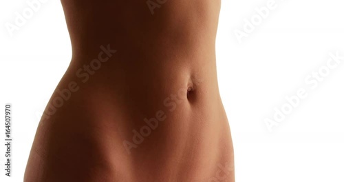 Close up of young Caucasian woman's flat stomach on white background with copyspace. Closeup of white female's fit abdomen and tan skin in studio with copy space . 4k 