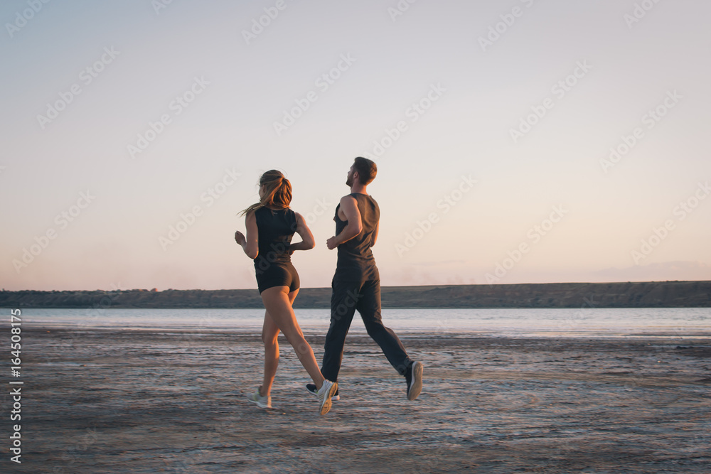 Fototapeta premium Potomstwa dobierają się bieg na plaży przy wschodu słońca tłem