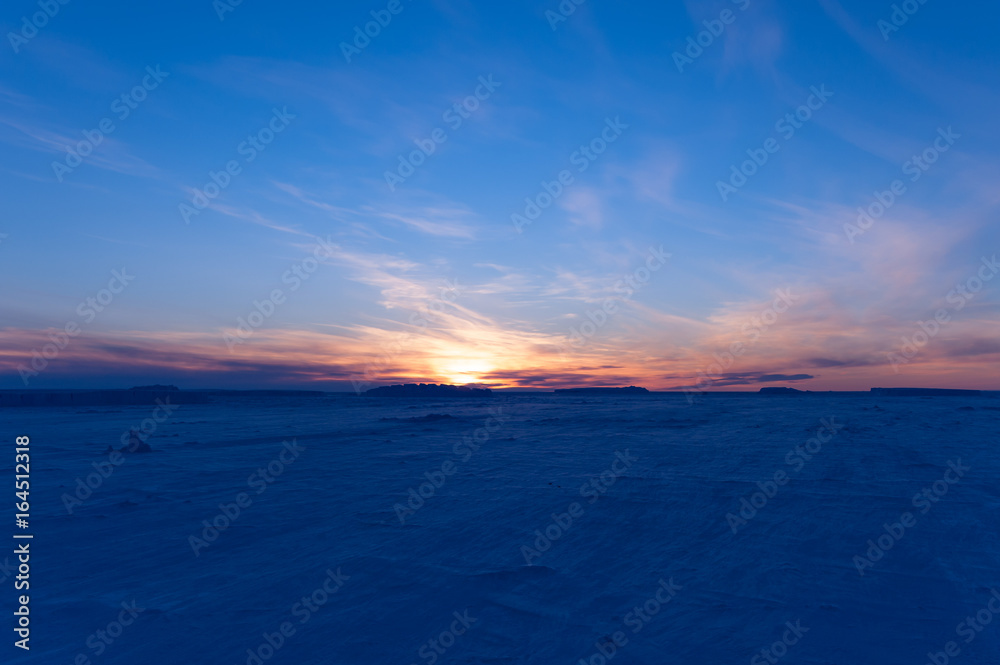 Obraz premium The frozen Weddell Sea in Antarctica at sunset with icebergs in the disdance.
