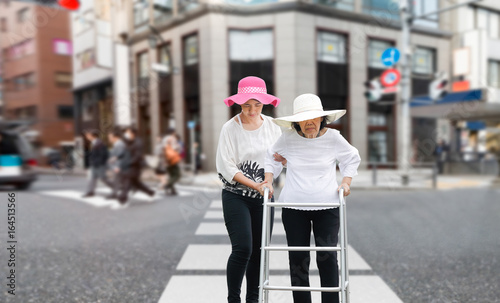 Daughter take care elderly woman walking across the street in downtown © toa555