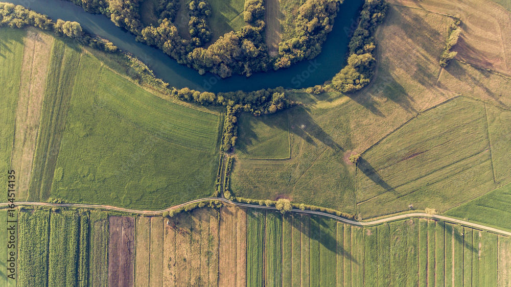 River bend surrounded by fields from bird's eye view.
