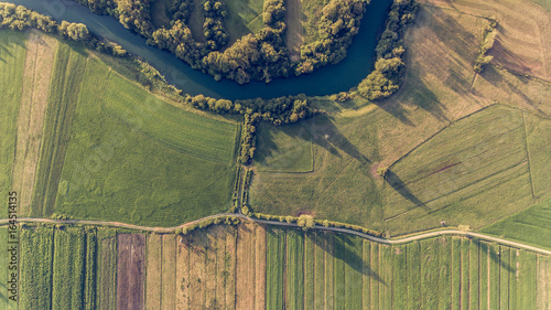 Obraz na płótnie River bend surrounded by fields from bird's eye view. w salonie