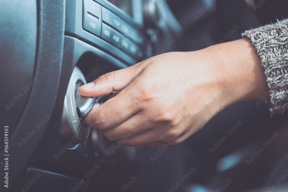 Woman hand adjusting car air conditioning system while driving a car in vintage color tone