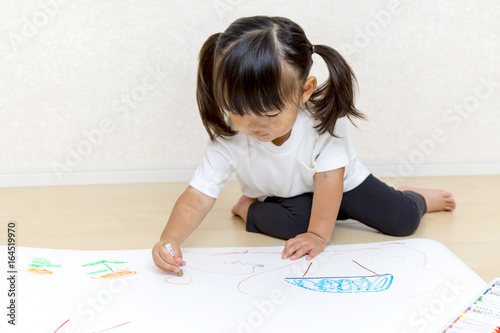 フローリングで絵を描く幼い女の子