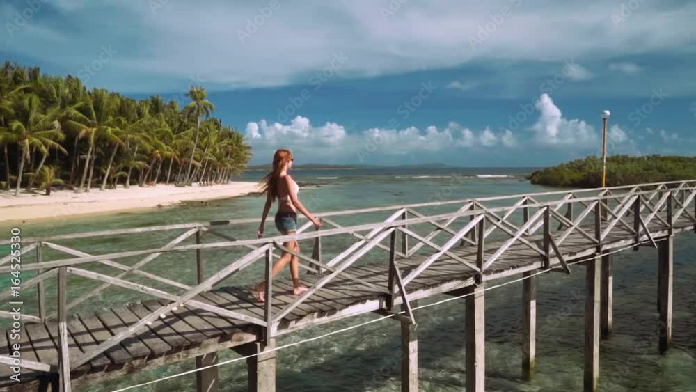 Young woman walking on boardwalk in ocean close to tropical island - Cloud 9 boardwalk on Siargao Island, Philippines Young woman walking on boardwalk in ocean close to tropical island - Cloud 9 boardwalk on Siargao Island, Philippines