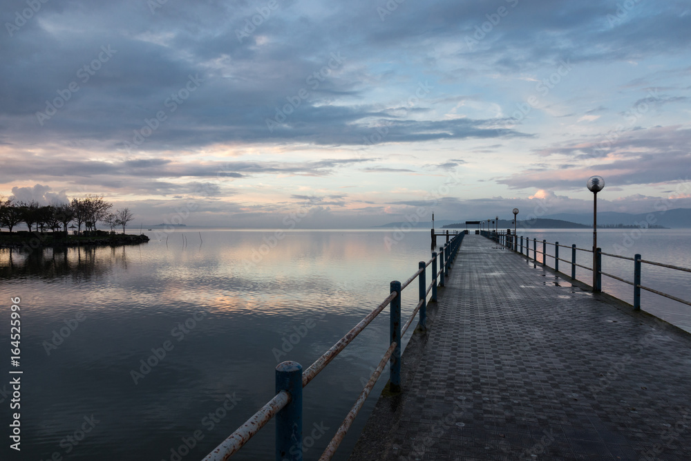 A first person view of a pier under a beautiful sky at sunset, reflecting on water