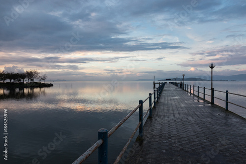 A first person view of a pier under a beautiful sky at sunset  reflecting on water
