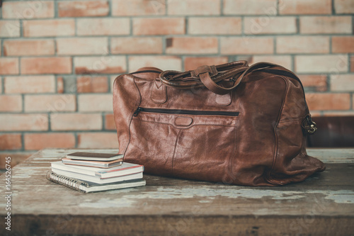 Men's accessories with Dark brown leather bags on wooden table over brick wall background,color vintage style,Thailand