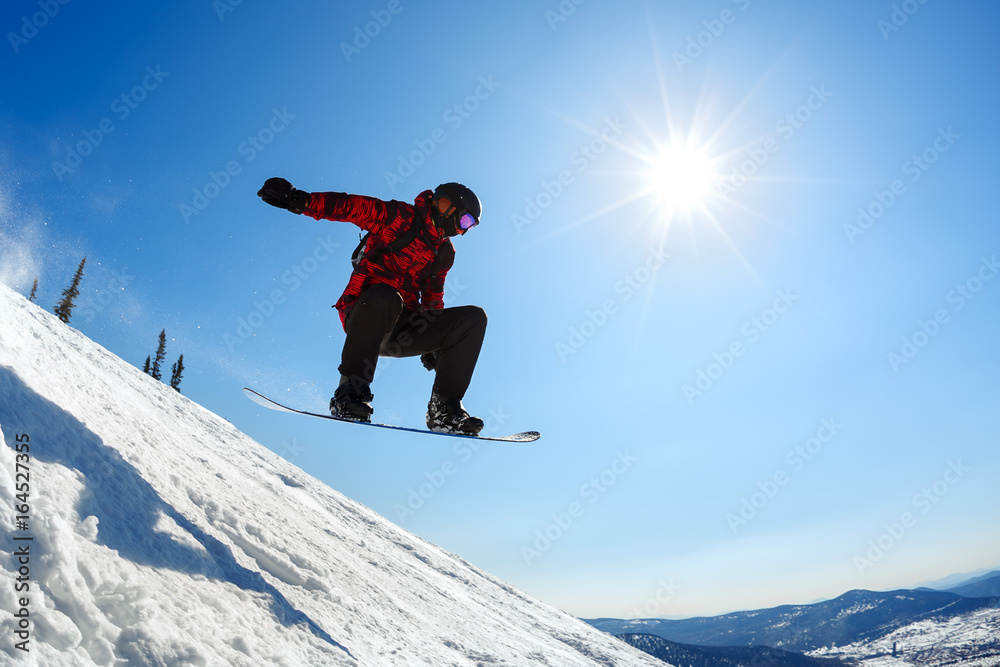 Snowboarder jumping from the springboard against the sky