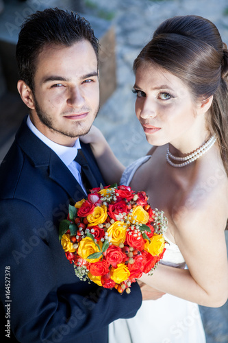 Wife and groom in wedding day looking up at the camera. Just married couple