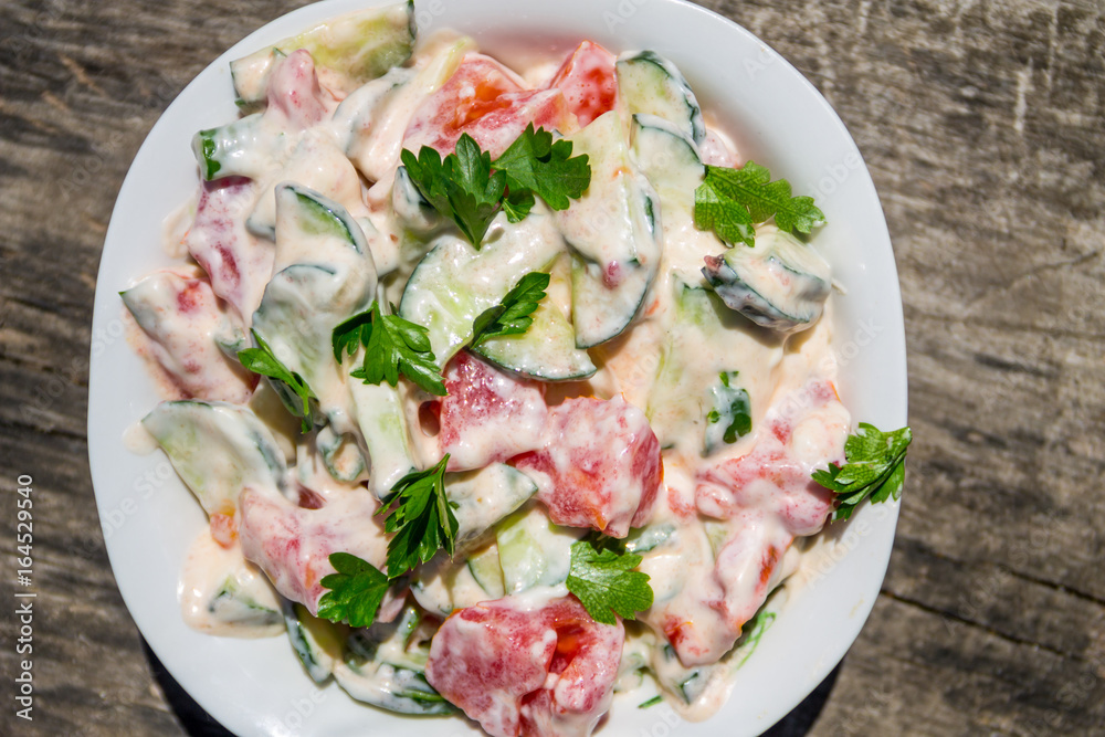 Fresh salad with tomato, cucumber, onion, parsley and mayonnaise on rustic wooden table Fresh salad with tomato, cucumber, onion, parsley and mayonnaise on rustic wooden table