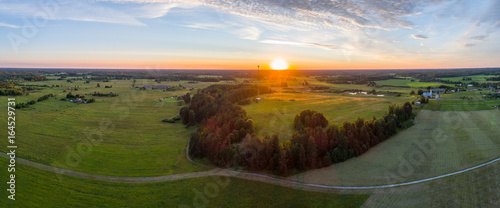 Beautiful sunset over the small town. Fields and trees around. Aerial photography panorama.