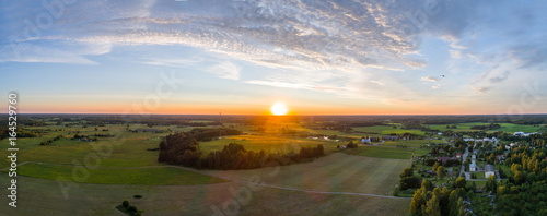 Fototapeta Naklejka Na Ścianę i Meble -  Beautiful sunset over the small town. Fields and trees around. Aerial photography panorama.