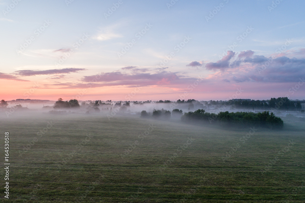 Aerial view of fields with fog at amazing sunset. Summer nature landscape.