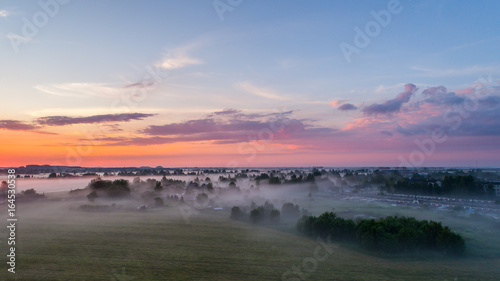 Aerial view of city in fog at amazing sunset. Summer nature landscape.