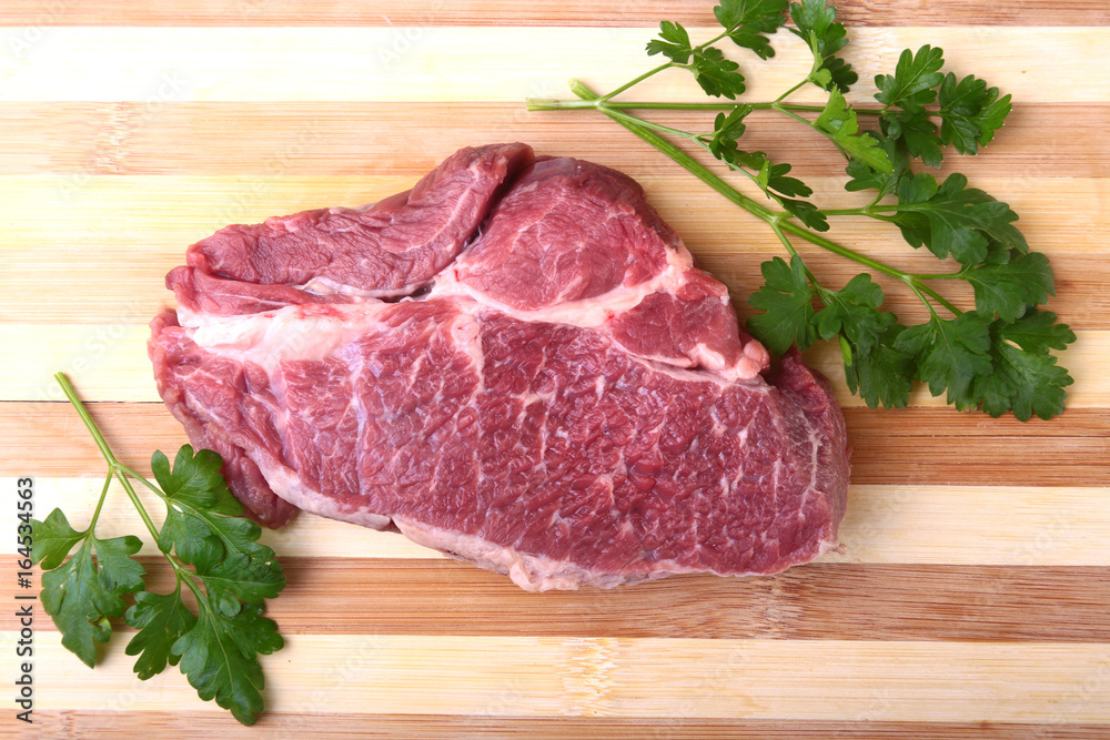 Raw beef steak with spices Leaves of coriander on wooden cutting board. Ready for cooking. Raw beef steak with spices Leaves of coriander on wooden cutting board. Ready for cooking.