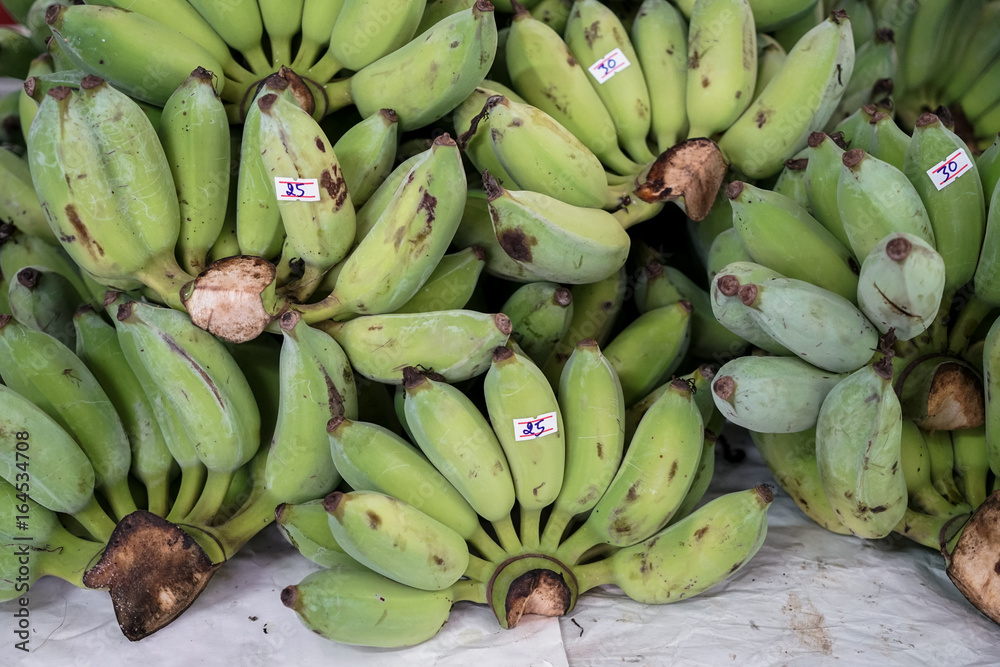 Bunches of raw green cultivated banana in local market with price tag