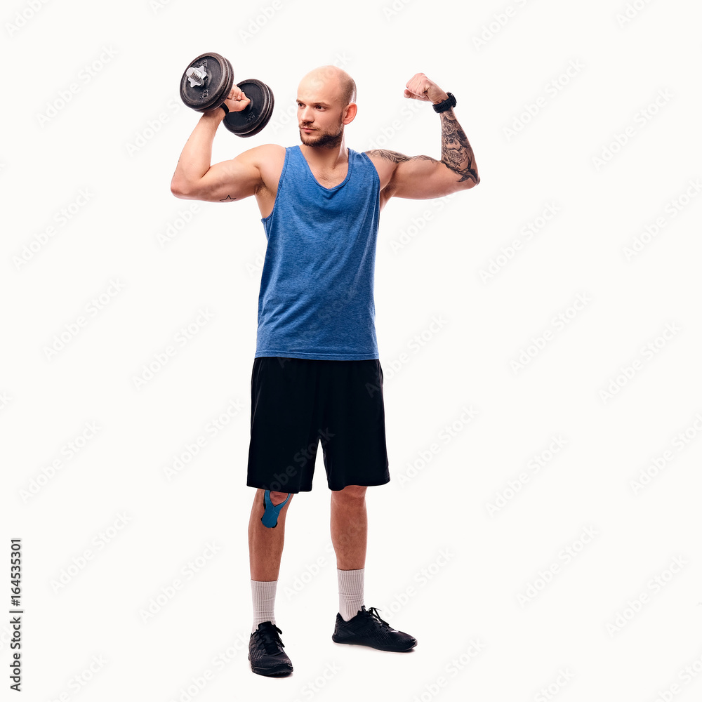 Shaved head male holds dumbbell. Shaved head male holds dumbbell.