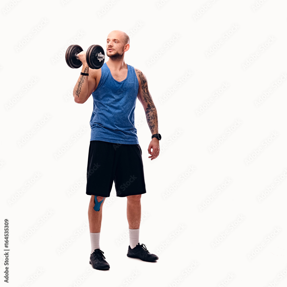 Shaved head male holds dumbbell. Shaved head male holds dumbbell.