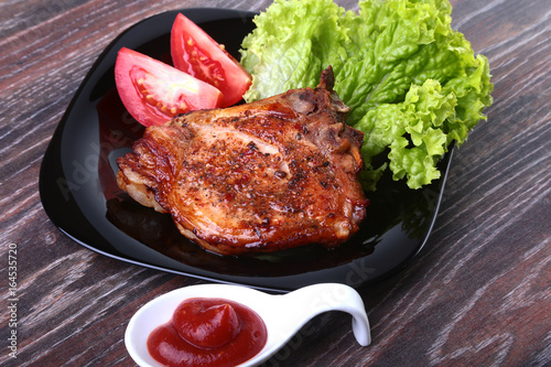 grilled pork chops with tomato, leaves lettuce and ketchup on plate.