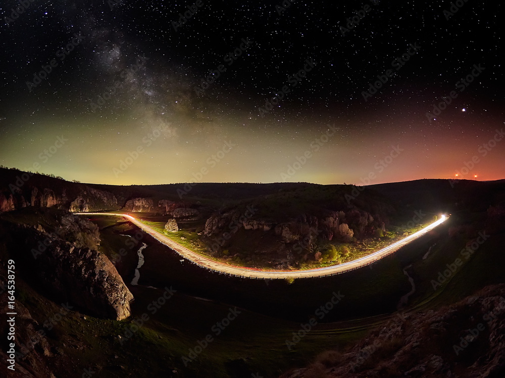 Night sky with milky way and stars, night road illuminated by car's ...