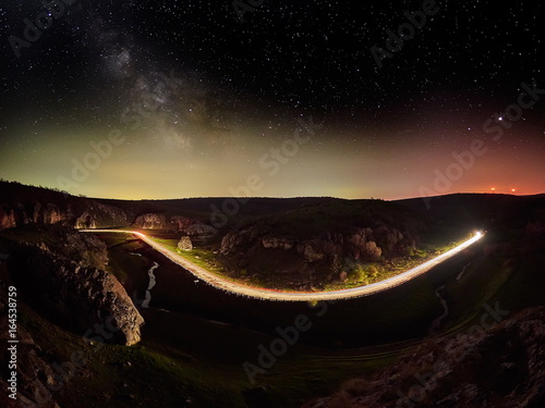 Fototapeta Naklejka Na Ścianę i Meble -  Night sky with milky way and stars, night road illuminated by car's light trails