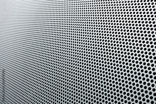 Gray metal background, round perforated metal texture with reflections