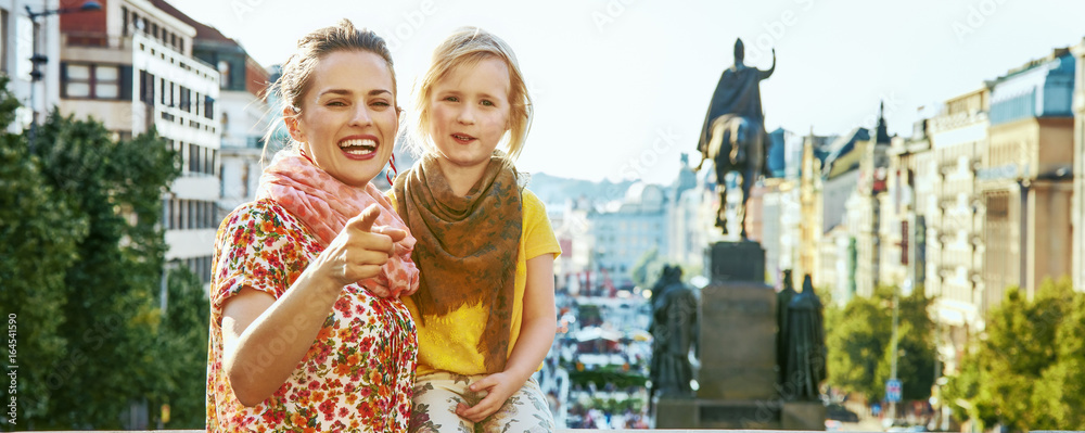 happy mother and child tourists in Prague pointing in camera