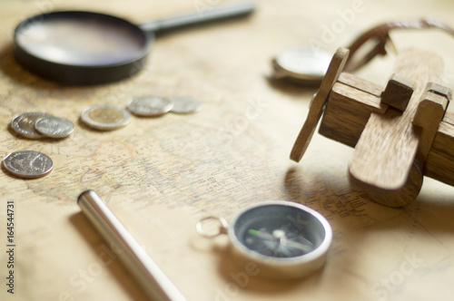 Compass ,coins and Wooden plane on world map, selective focus , vintage style.Travel and holiday concept.