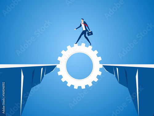 Businessman using cog gear to cross through the gap between hill.  Business risk and success concept.
