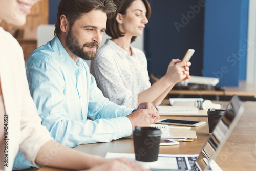 Cheerful youthful guy with beard and women working in office