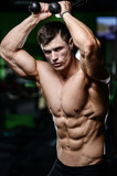 Muscular handsome athletic bodybuilder fitness model posing after exercises in gym on diet .