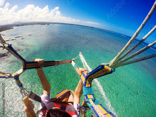View of couple parasailing with the speed boat in the sea background.