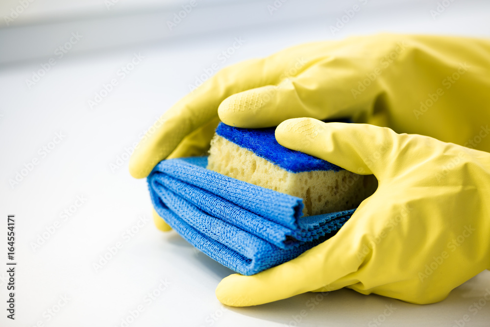 hand  in a rubber yellow glove holding sponge. 