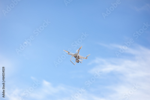 Quadcopter or drone holds video using a digital camera on the blue sky background