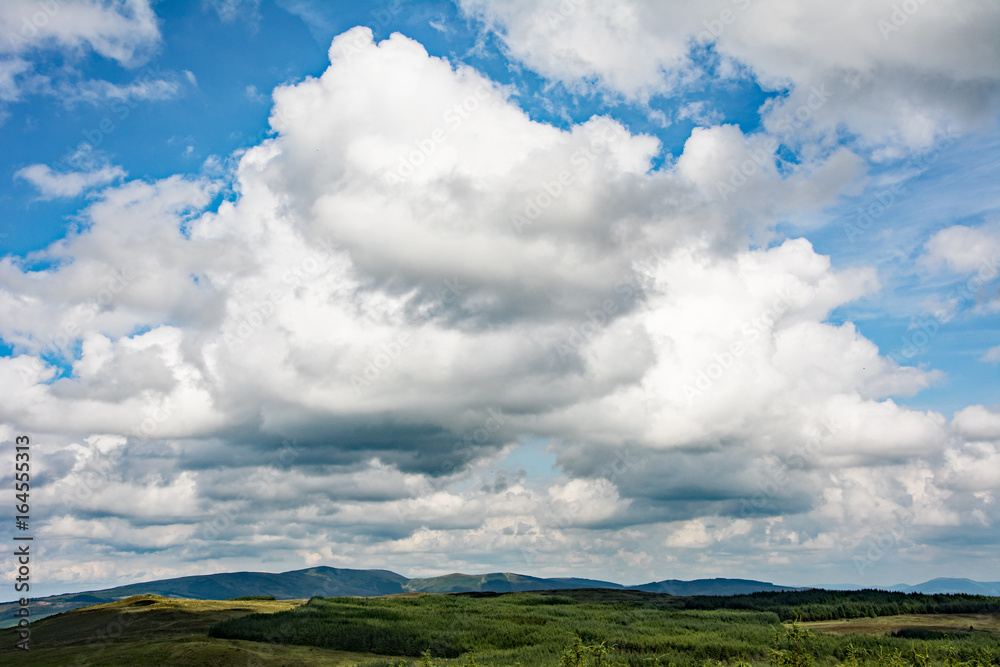 White clouds on the blue sky over Irish hills and mountains White clouds on the blue sky over Irish hills and mountains