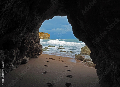 window view on footprints on a sandy beach leading to the blue sea