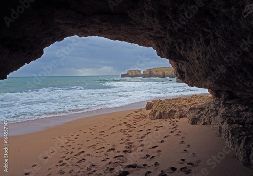 sand beach with sandstone window and foot prints and cliffs