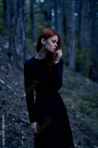 Beautiful young woman in a long dress in the forest