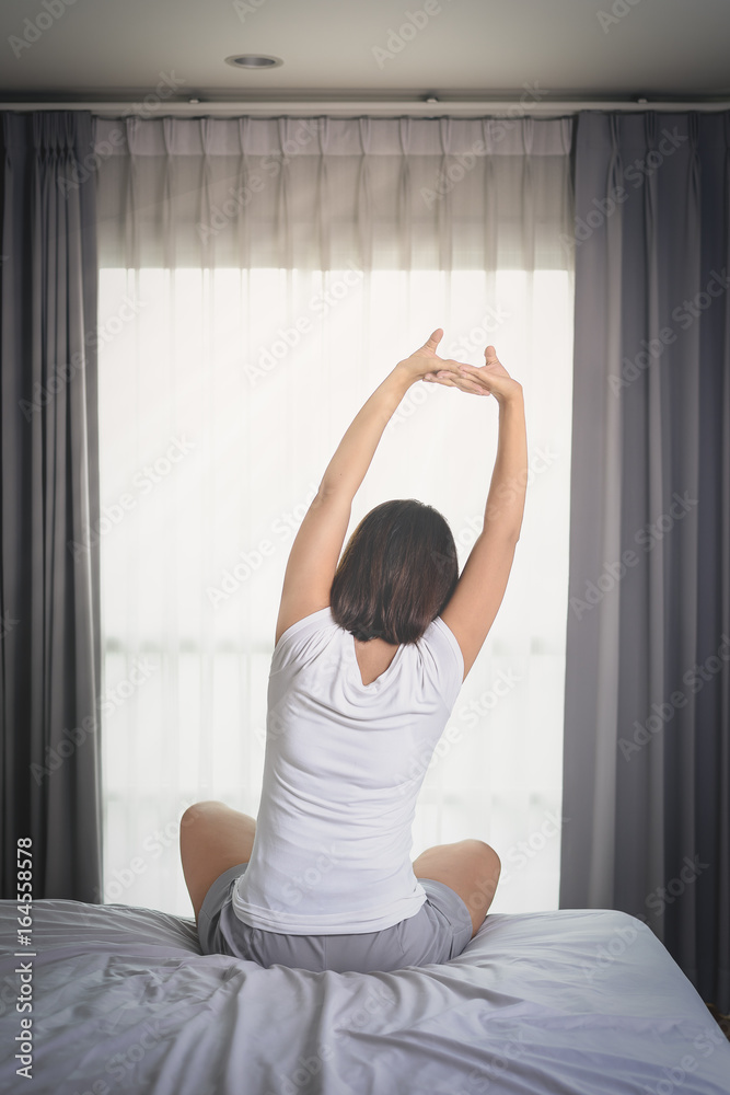 Asian Woman stretching in bed after wake up