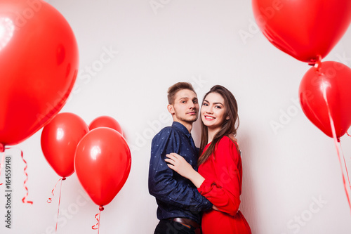 young couple in love smiling over a white background with air balloons © aemstock