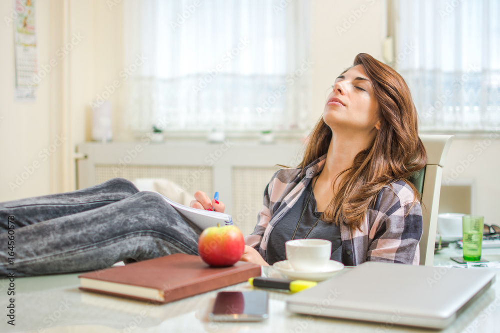 Young female student sleeping on chair near the desk at home. Young female student sleeping on chair near the desk at home.