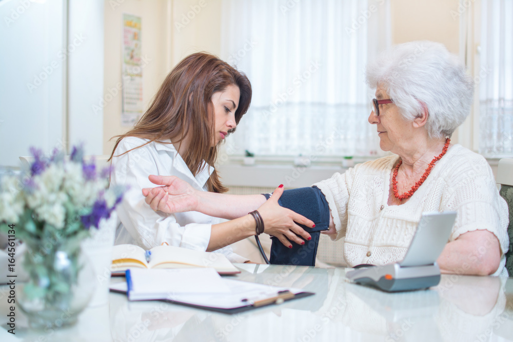 Nurse putting on blood pressure monitor to senior woman's hand. Nurse putting on blood pressure monitor to senior woman's hand.
