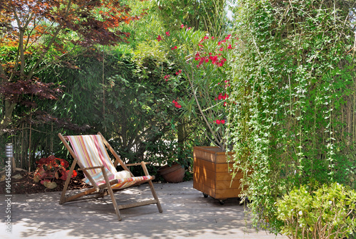 chaise longue sur terrasse en bois dans verdure