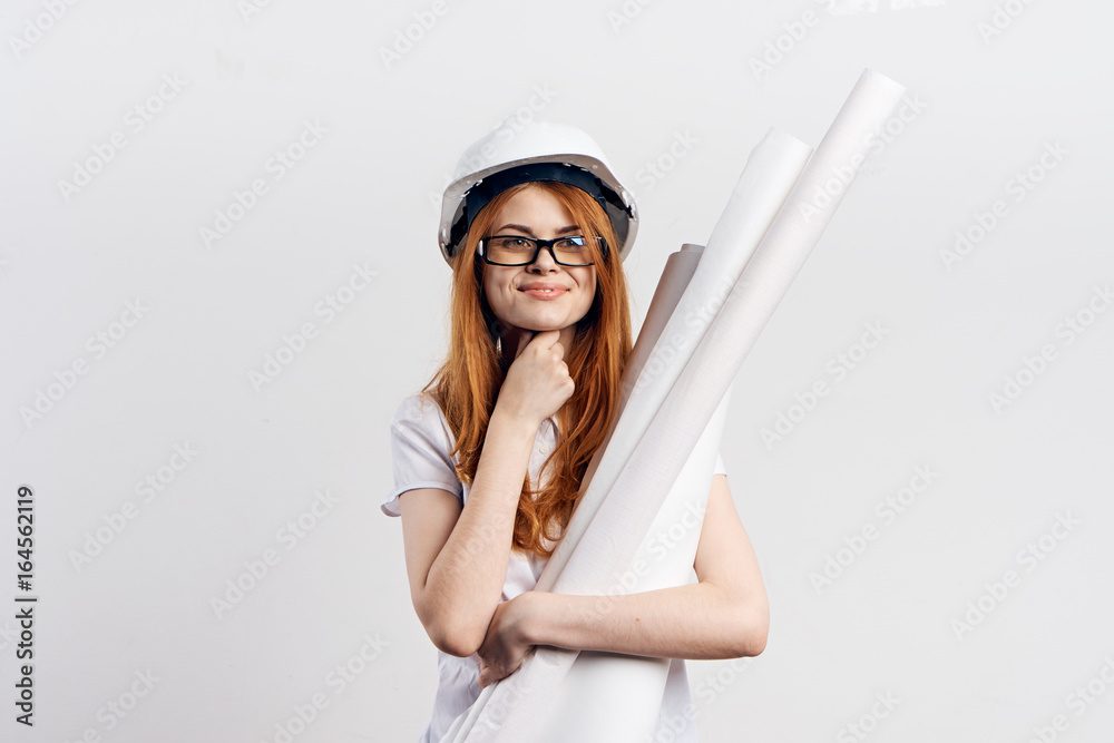Young beautiful woman on white isolated background holds blueprints, engineer