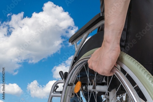 Handicapped disabled man sitting on wheelchair against blue sky. photo