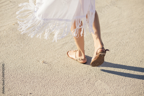 Female legs in sandals go on a desert sand photo