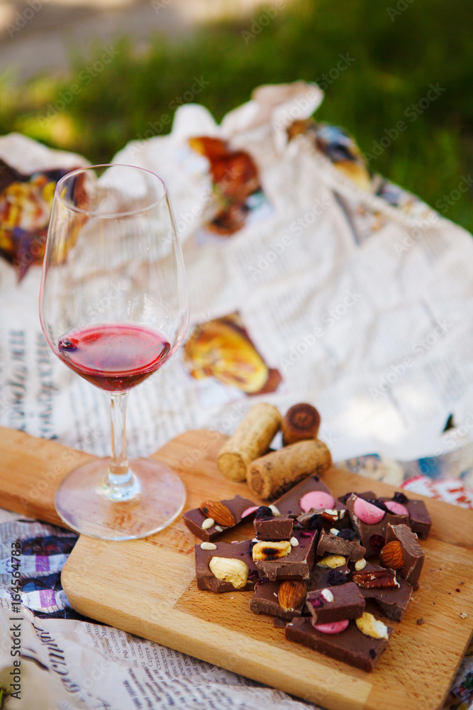 Glass with red wine and pieces of chocolate with nuts and raisins