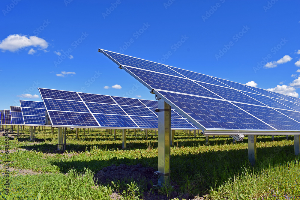 Solar panels on field. Clear sky with a few small clouds on background. Solar panels on field. Clear sky with a few small clouds on background.